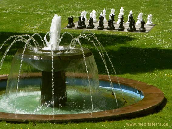 Springbrunnen mit Schachspiel im Hintergrund auf einer Wiese