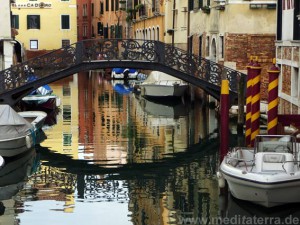 Brücke in Venedig mit bunter Wasserspiegelung und Booten