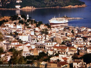 Blick auf die Hautpstadt der Insel Skiathos mit weißem Schiff im Hafen und Inselchen drumherum